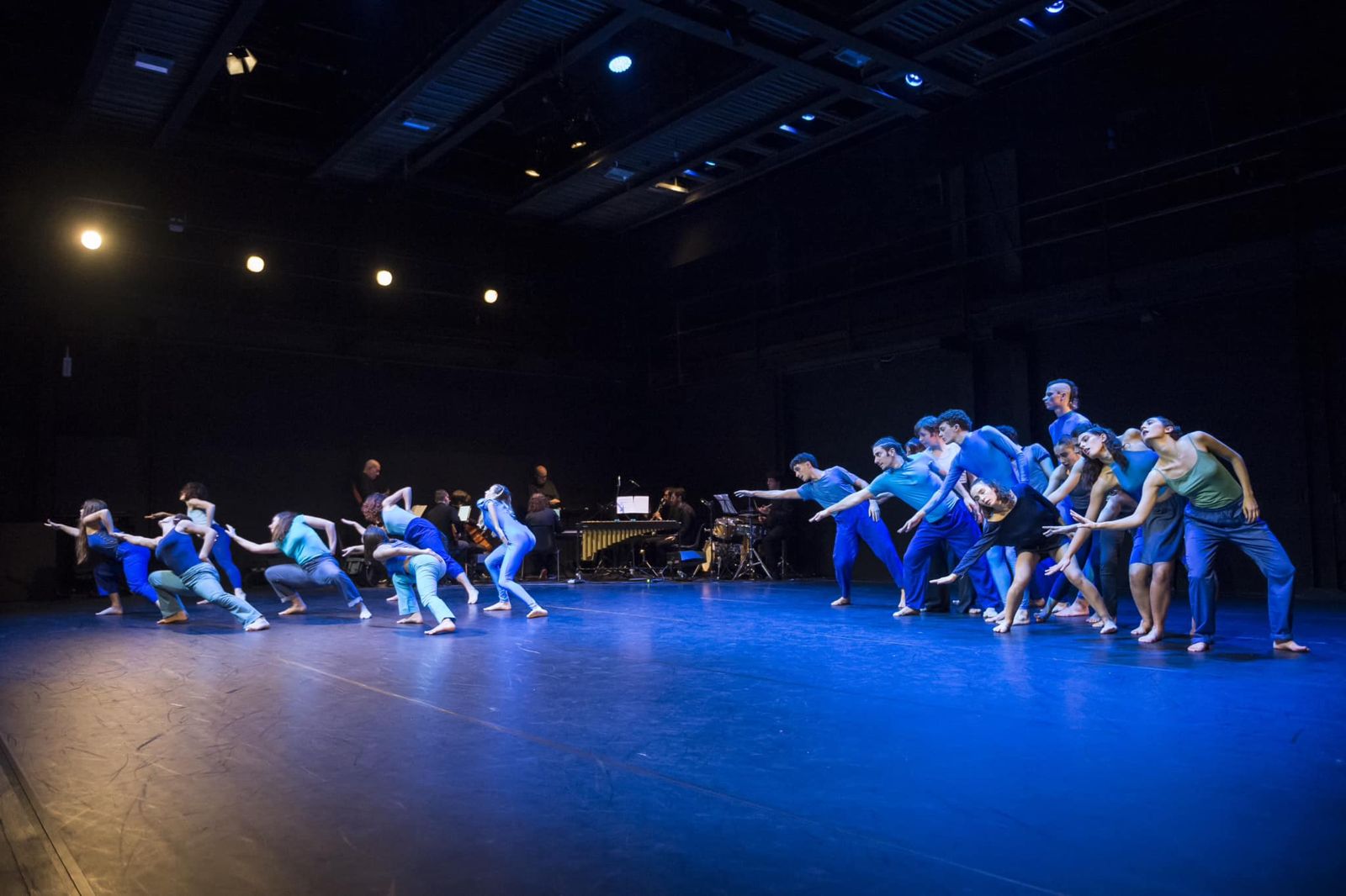 L'ensemble di Muddica 7 in due linee contrapposte sul palco di Scenario Pubblico, con i musicisti sullo sfondo